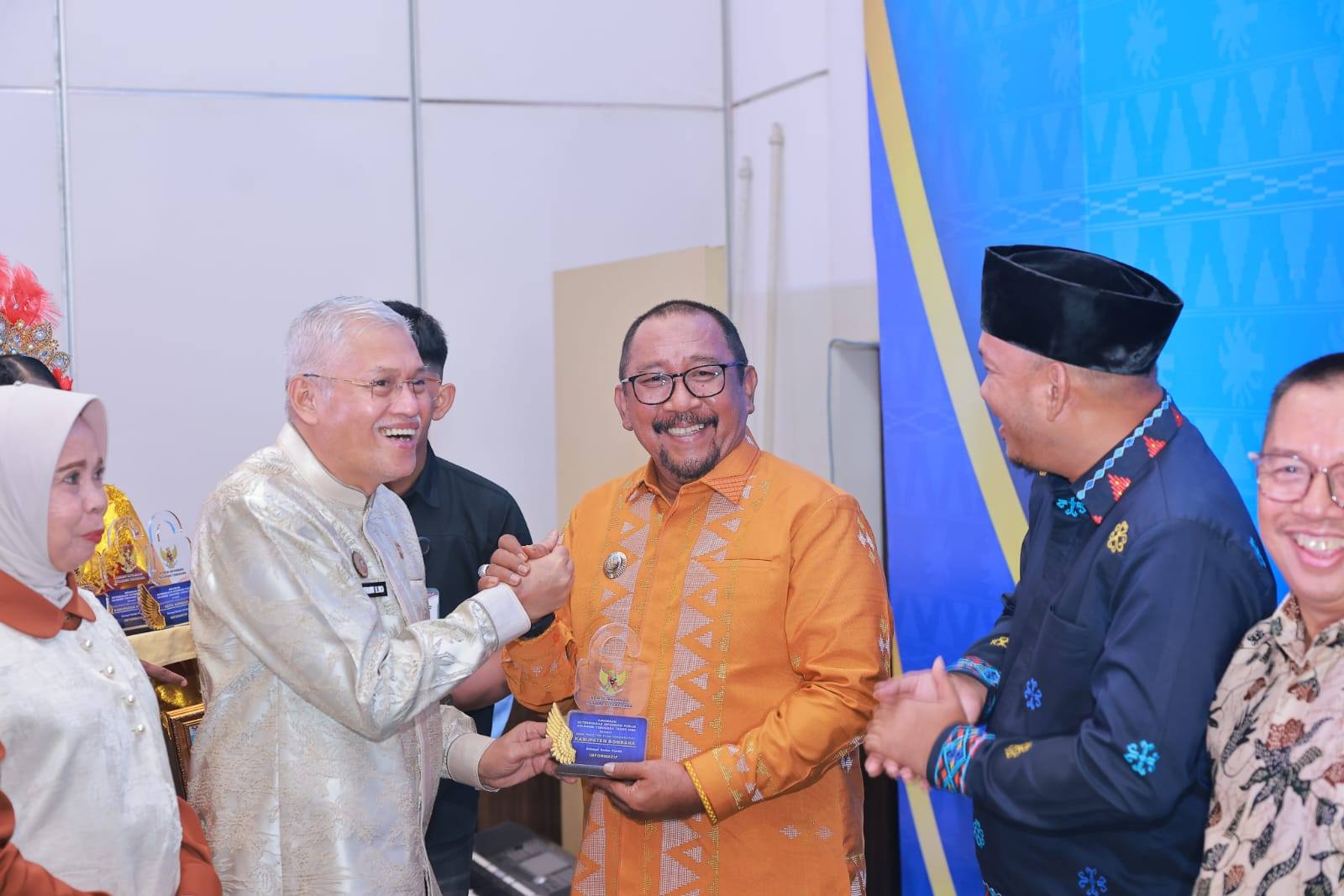 Ketgam: Bupati Bombana (Kemeja Batik Orange) Ir. H. Burhanuddin, M.Si Saat Menerima Penghargaan yang Diserahkan Langsung Oleh Sekrtaris Daerah Sulawesi Tenggara Drs. H Asrun Lio., M.Hum.,Ph.D, dalam Penganugerahan Keterbukaan Informasi Publik 2025 di Ballroom Hotel Claro Kendari, Senin 16 Desember 2025