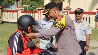 Ketgam: Kapolres Bombana, AKBP Eko Sutomo, S.I.K., M.I.K., saat memasangkan helm kepada pengendara dalam kegiatan simpati di jalan raya, di depan Mako Polres Bombana, Selasa 10 Februari 2026