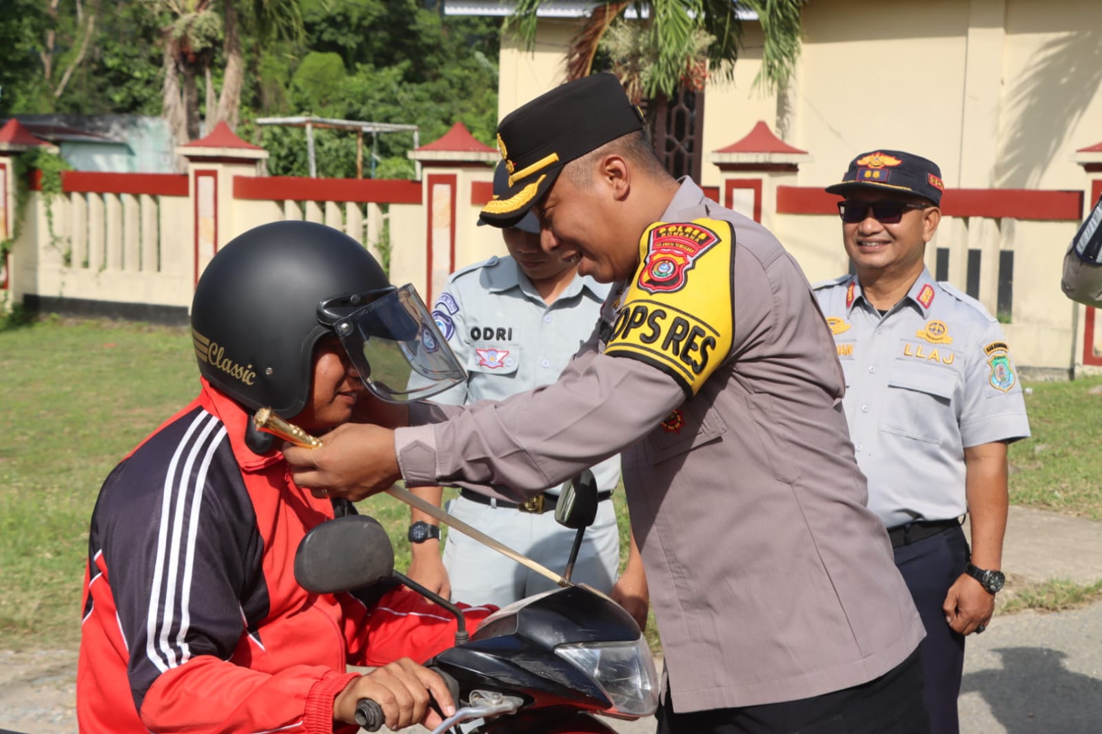 Ketgam: Kapolres Bombana, AKBP Eko Sutomo, S.I.K., M.I.K., saat memasangkan helm kepada pengendara dalam kegiatan simpati di jalan raya, di depan Mako Polres Bombana, Selasa 10 Februari 2026